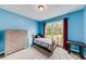 Bedroom with blue walls, carpet floors, and large window overlooking the front yard at 2205 Castle Royale Dr, Lawrenceville, GA 30043