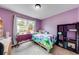 Bedroom with purple walls, carpet floors, and large window overlooking the front yard at 2205 Castle Royale Dr, Lawrenceville, GA 30043
