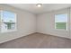 Bright bedroom featuring neutral carpeting, white walls, and natural light from the two windows at 6935 Melody Dr, Buford, GA 30518