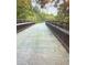 A concrete bridge with a brown railing surrounded by lush greenery on either side, leading towards mature trees at 6935 Melody Ridge Rd, Buford, GA 30518