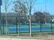 Tennis courts with dark green fencing and well maintained blue and green playing surface, surrounded by wintery, bare trees at 6935 Melody Ridge Rd, Buford, GA 30518