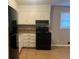 Galley kitchen with white cabinets and black appliances at 10650 Panhandle Rd, Hampton, GA 30228