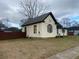 Side view of a yellow house needing repairs, featuring a fenced yard at 7163 Swift St, Lithonia, GA 30058