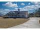 Well-designed gray home with a cozy porch and long driveway, set against a backdrop of lush greenery at 85 Woodfin Way, Social Circle, GA 30025