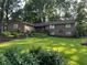 Beautiful brick home featuring manicured lawn, mature trees, and colorful flower beds at 747 Dogwood Cir, Norcross, GA 30071
