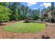 Expansive backyard with lush lawn, mature trees, and an outdoor kitchen area next to the large swimming pool at 5330 Lake Redwine Nw Cv, Acworth, GA 30101