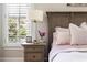 Bedroom detail featuring a nightstand with lamp, floral arrangement and view through plantation shutters at 5330 Lake Redwine Nw Cv, Acworth, GA 30101