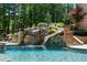 Resort-style pool with waterfall feature and slide, surrounded by lush landscaping at 5330 Lake Redwine Nw Cv, Acworth, GA 30101