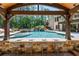 Outdoor bar area with seating overlooking a luxurious pool with a waterfall and slide, set in a wooded backyard at 5330 Lake Redwine Nw Cv, Acworth, GA 30101