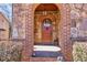 Inviting arched stone entryway with a wooden door and decorative lighting at 4595 Carriage Walk Ln, Cumming, GA 30040