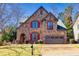Beautiful stone house with a well-manicured lawn, attached garage, and decorative red window shutters at 4595 Carriage Walk Ln, Cumming, GA 30040