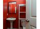 Small bathroom with red walls, pedestal sink, and toilet at 991 Greenwood Ne Ave, Atlanta, GA 30306