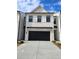 Two-story townhome with white brick exterior, black garage door, and landscaping at 1946 Westwind Street (Lot 132), Lawrenceville, GA 30043