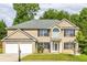 Two-story brick house with a two-car garage and landscaped lawn at 1598 Blue Spruce Ln, Conyers, GA 30012