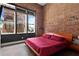 Main bedroom featuring exposed brick, large windows, and a modern platform bed with red linens at 350 Peters Sw St # 3, Atlanta, GA 30313