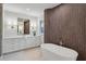 Bright bathroom featuring a standalone tub with stainless fixtures, wood detailing, vanity, mirror and marble flooring at 165 Grayton Ln, Roswell, GA 30075