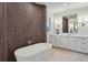 Bright bathroom featuring a standalone tub with stainless fixtures, wood detailing, vanity, mirror and marble flooring at 165 Grayton Ln, Roswell, GA 30075