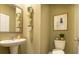 Charming powder room featuring a pedestal sink, decorative plants, a stylish mirror, and artistic wall decor at 2456 Bayberry St, Acworth, GA 30101