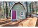 Well-maintained storage shed with a red door, in wooded backyard at 1237 Torrey Pl, Dacula, GA 30019