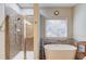 Modern bathroom with tiled shower, soaking tub under the window and sleek fixtures at 588 Myrtle Trace Ln, Suwanee, GA 30024