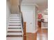 Staircase featuring hardwood steps, a white riser and a partial view of the kitchen at 588 Myrtle Trace Ln, Suwanee, GA 30024