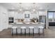 Modern white kitchen featuring a large island with seating, stainless steel appliances, and stylish lighting at 1603 Caldwell Bend Ln, Dacula, GA 30019