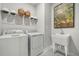 Functional laundry room with modern washer, dryer, utility sink, and stylish artwork at 512 Altamaha Ct, Locust Grove, GA 30248