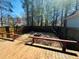 View of fenced backyard area with gravel and a fire pit, plus a wooden deck and forest in the background at 850 Airline Rd, Mcdonough, GA 30252