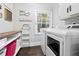 Bright laundry room features white washer and dryer, storage and shelving, and a window at 200 Mcguirts Bridge Rd, Covington, GA 30014