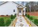 Charming white home entrance with a decorated door, stone walkway, and lush landscaping at 410 N Carroll N St, Bowdon, GA 30108