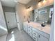 Modern bathroom with dual sinks, framed mirror, tiled floor, and a view into the tiled shower at 44 Easton Park Blvd, Dallas, GA 30157