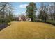 Large backyard with grassy lawn, mature trees, and a glimpse of a pool at 100 Dunwoody Creek Ct, Atlanta, GA 30350