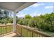 Covered back porch with wood railing offers scenic views of lush greenery and a peaceful outdoor space at 6745 Dahlgren Ct, Cumming, GA 30028