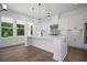 Modern white kitchen featuring an island with seating, stainless steel appliances, and pendant lighting at 6745 Dahlgren Ct, Cumming, GA 30028