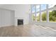 Spacious living room featuring hardwood floors, a fireplace, and large windows with backyard views at 6745 Dahlgren Ct, Cumming, GA 30028