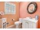 Functional half-bathroom with a peach walls, a modern vanity, and a round mirror at 5545 Woodsong Trl, Dunwoody, GA 30338