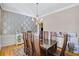 Dining room features hardwood floors, a chandelier, wallpapered accent wall, and a large table set for eight at 2025 Fife Ridge Ct, Roswell, GA 30075