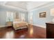 Light blue bedroom with hardwood floors, shutters, and tray ceilings, providing a bright and inviting space at 918 Big Horn Holw, Suwanee, GA 30024