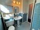 View of a bathroom with blue tiling, pedestal sink, and a storage cabinet over the toilet at 6070 Blackhawk Se Trl, Mableton, GA 30126