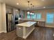 Bright kitchen features an island with quartz countertop, stainless steel appliances, gray cabinets, and modern pendant lighting at 391 Lincoln St, Woodstock, GA 30188