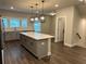Bright kitchen features an island with quartz countertop, gray cabinets, hardwood floors, and modern pendant lighting at 391 Lincoln St, Woodstock, GA 30188