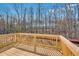 View of natural wood deck overlooks wooded property with trees in background on sunny day at 31 Bennett Farm Dr, Loganville, GA 30052