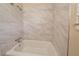 Clean bathtub and shower with marble-style tile at 2476 Brentford Pl, Decatur, GA 30032