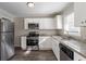 Bright kitchen with stainless steel appliances, granite countertops, white cabinetry, and vinyl floors at 2424 West Rd, Riverdale, GA 30296