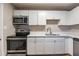 Bright kitchen featuring stainless steel appliances, white cabinets, and light countertops with hardwood floors at 5938 Baywood Ln, Riverdale, GA 30296
