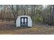 Charming white storage shed with black trim, nestled amongst mature trees in a spacious backyard at 219 Thorncrest, Stockbridge, GA 30281