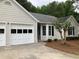 Tan house with white garage doors and landscaping at 2301 River Station Ter, Woodstock, GA 30188