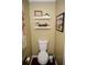 Small bathroom with toilet, decorative shelving and artwork at 4770 Quail Hunt Ct, Powder Springs, GA 30127