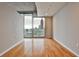 Bright, empty room with hardwood floors and large windows offering stunning views of the city skyline at 860 Peachtree Ne St # 2506, Atlanta, GA 30308