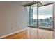 Bright, empty room with hardwood floors and large windows offering stunning views of the city skyline at 860 Peachtree Ne St # 2506, Atlanta, GA 30308